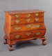A warm brown wooden dresser with flowing lines, ornate handles, and decorative clawed feet.