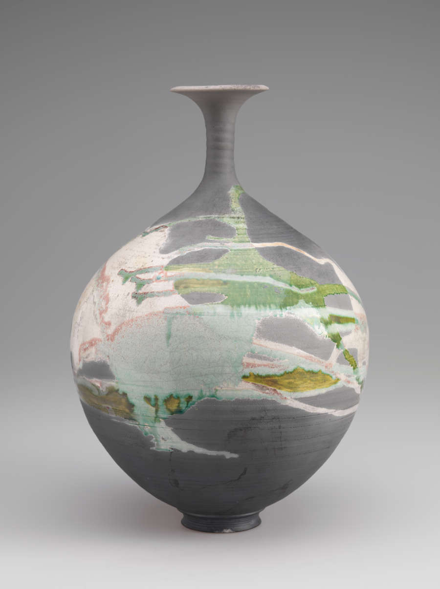 Different view of the same vessel covered in splashes of green and pink glaze.