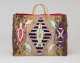 Fur-covered rectangular bag with thin looped handles, featuring central beaded seal silhouette within a black striped diamond, surrounded by red-blue patterned seals and multi-colored tassels, including a brown side panel. 