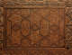 A close-up of an intricately carved wooden panel with geometric star patterns, and floral details, bordered by decorative edges. 