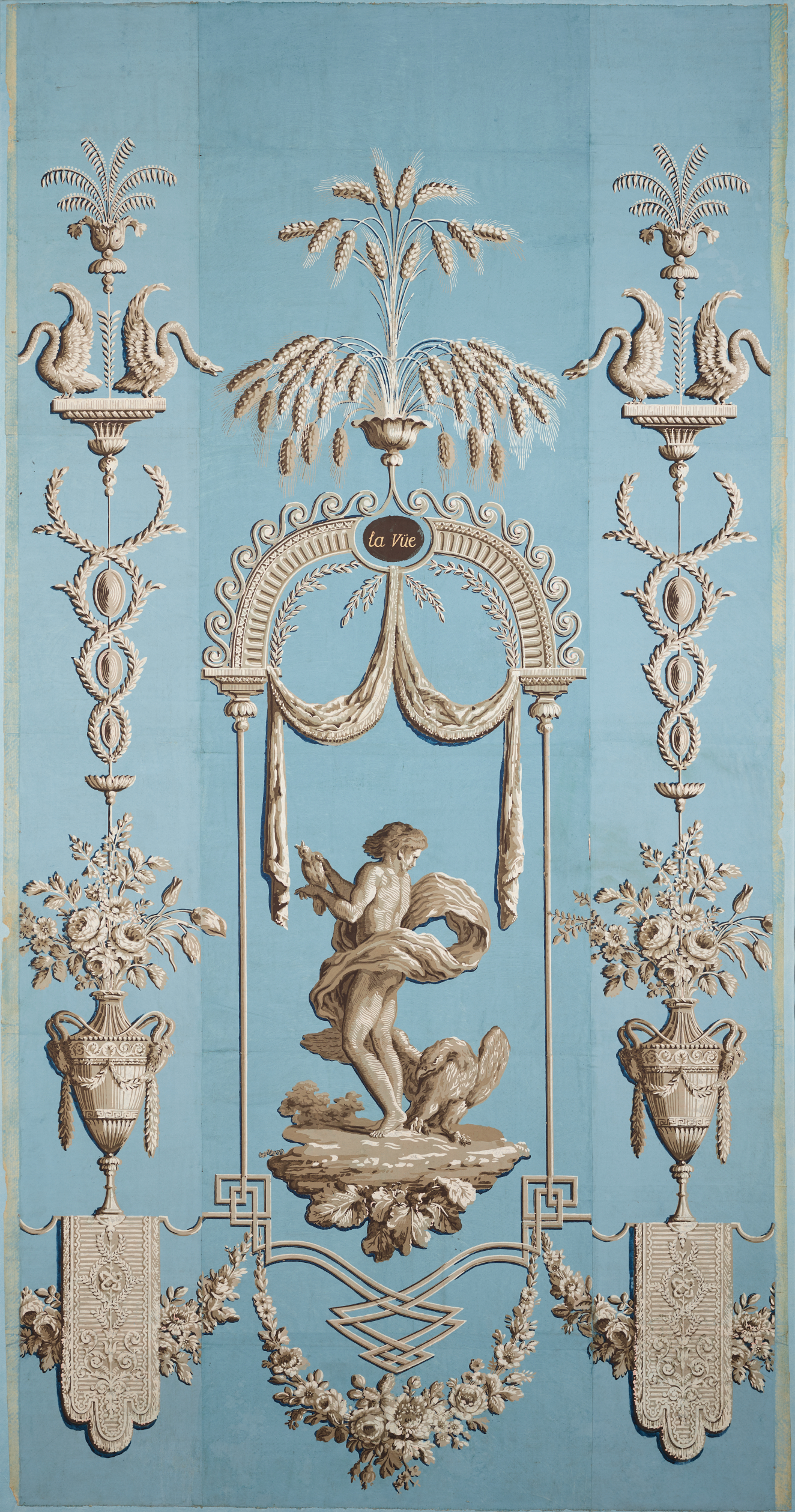 Narrow panel of vintage wallpaper featuring a central figure in a garden scene, surrounded by ornate ivory vase-like elements and botanical motifs. The design is set against a sky-blue backdrop.