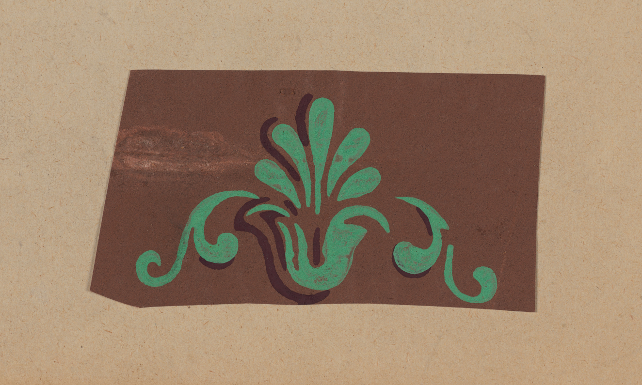 Decorative brown panel on a neutral backdrop featuring a green floral design with a fan-shaped center and flowing curves on either side.