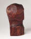 Back view of a carved wood sculpture depicting a head and neck. It is smooth, besides the bottom, where the wood is left uncarved and features cracks. The signature “Elizabeth Prophet” is thinly carved into the neck.