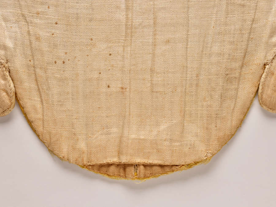 Close-up photo of off-white fabric and seams. The bottom has a rounded edge.