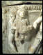 A detailed carving on a marble corner of a young figure carrying a bowl of fruit, draped in a sash, with a winged figure in the back.