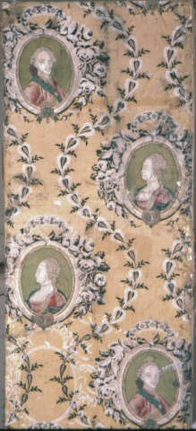 Tan, aged wallpaper of two repeating oval portraits, one of a man and the other a woman, both in elbarote dress encircled by delicate floral wreaths and leafy scrolls. 