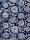 A decorative composition featuring intricate repeating white floral designs set against a deep blue background, with swirling vines and detailed blossoms.