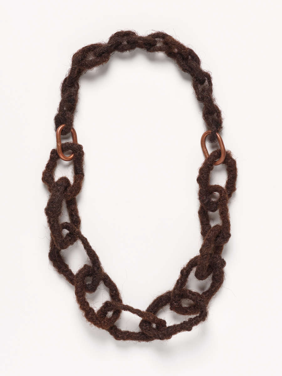 Photo of interlocking chain consisting of two metal rings and numerous oval links unevenly constructed from dark-brown fibers.