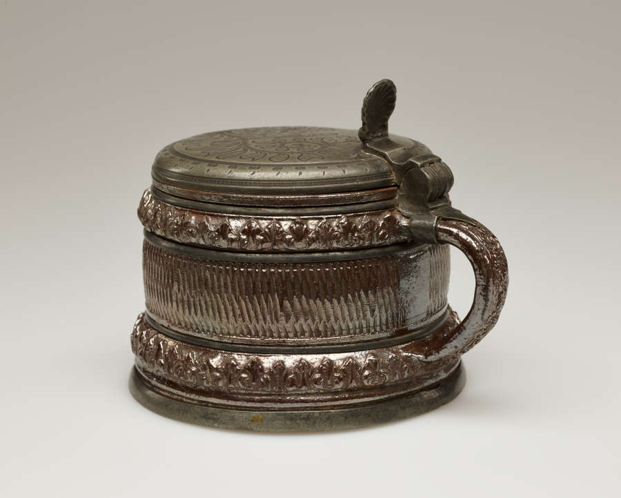 A brown and tan mug with a silver, scalloped rim.