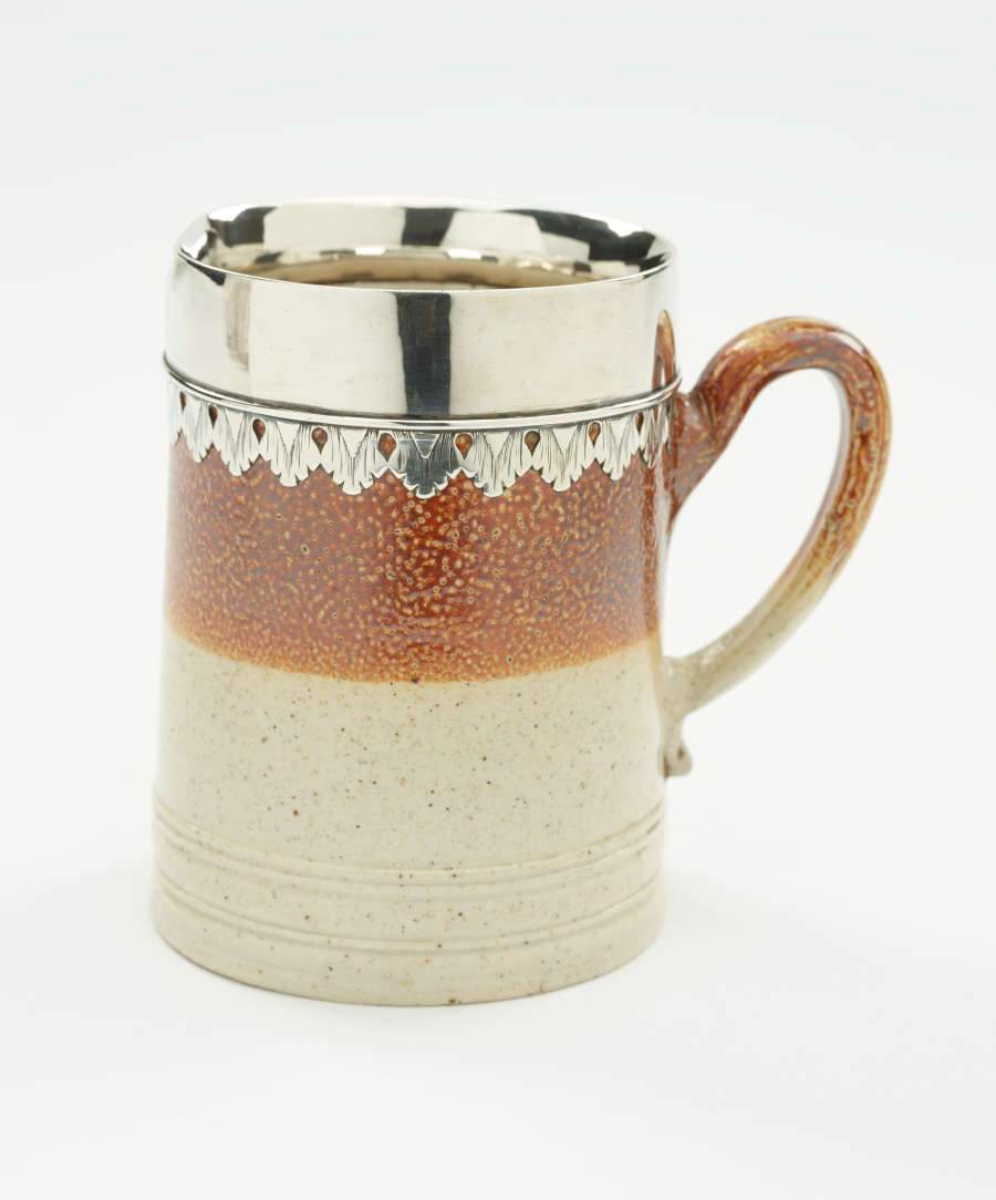 A brown and tan mug with a silver, scalloped rim.