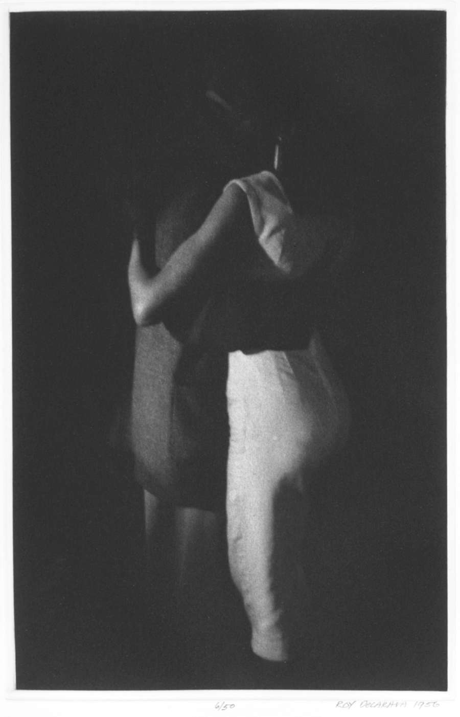 Black and white photo of two people dancing together, their arms around each other. Their faces and much of their bodies are completely obscured by shadows.