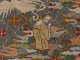 Robe’s back detail. A monk hunches over, praying, amongst earthy clouds below a white bird, against a dark background with a golden diagonal grid, within each square is a flower.