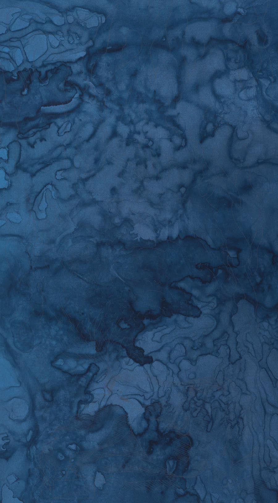 Dark, dense, blue marbling filles the entirety of a blue dyed sheet of paper. 