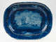 A platter with dark blue decorations depicting a coastal scene. Images of shells along the border.
