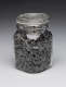 A glass jar tightly packed with gray and white striped sunflower seeds, sealed with a hinged metal clasp and a glass lid.