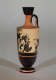 A tall, black and orange vase. Visible is a chipped black illustration of humans and small animals, surrounded by partial decorative patterns. 