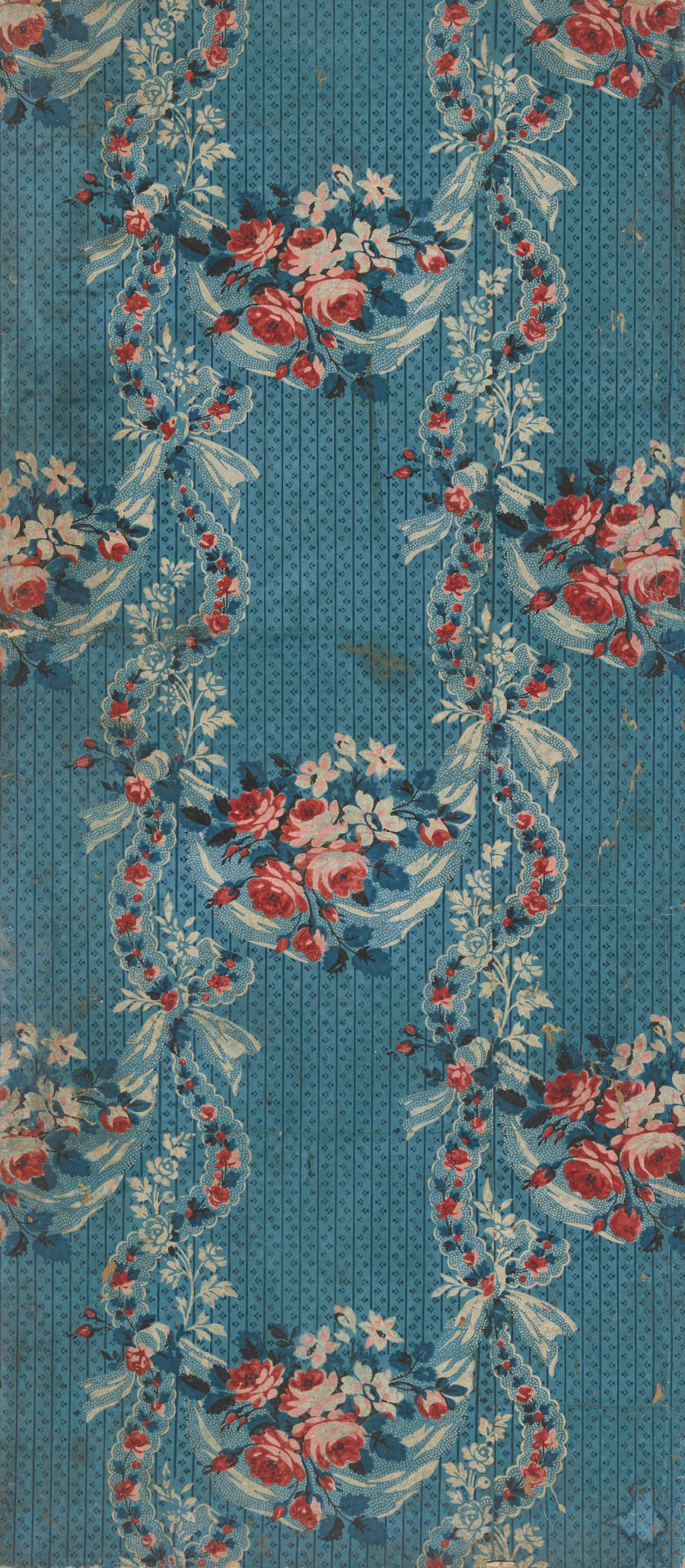 Narrow panel of stained, vintage wallpaper featuring a pattern of bright red roses and blue leaves on vertically aligned, undulating lines. The design is set against a dotted blue backdrop.