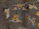 Detailed embroidery of birds in flight, surrounded by colorful cloud motifs, set against a gold lattice background. 