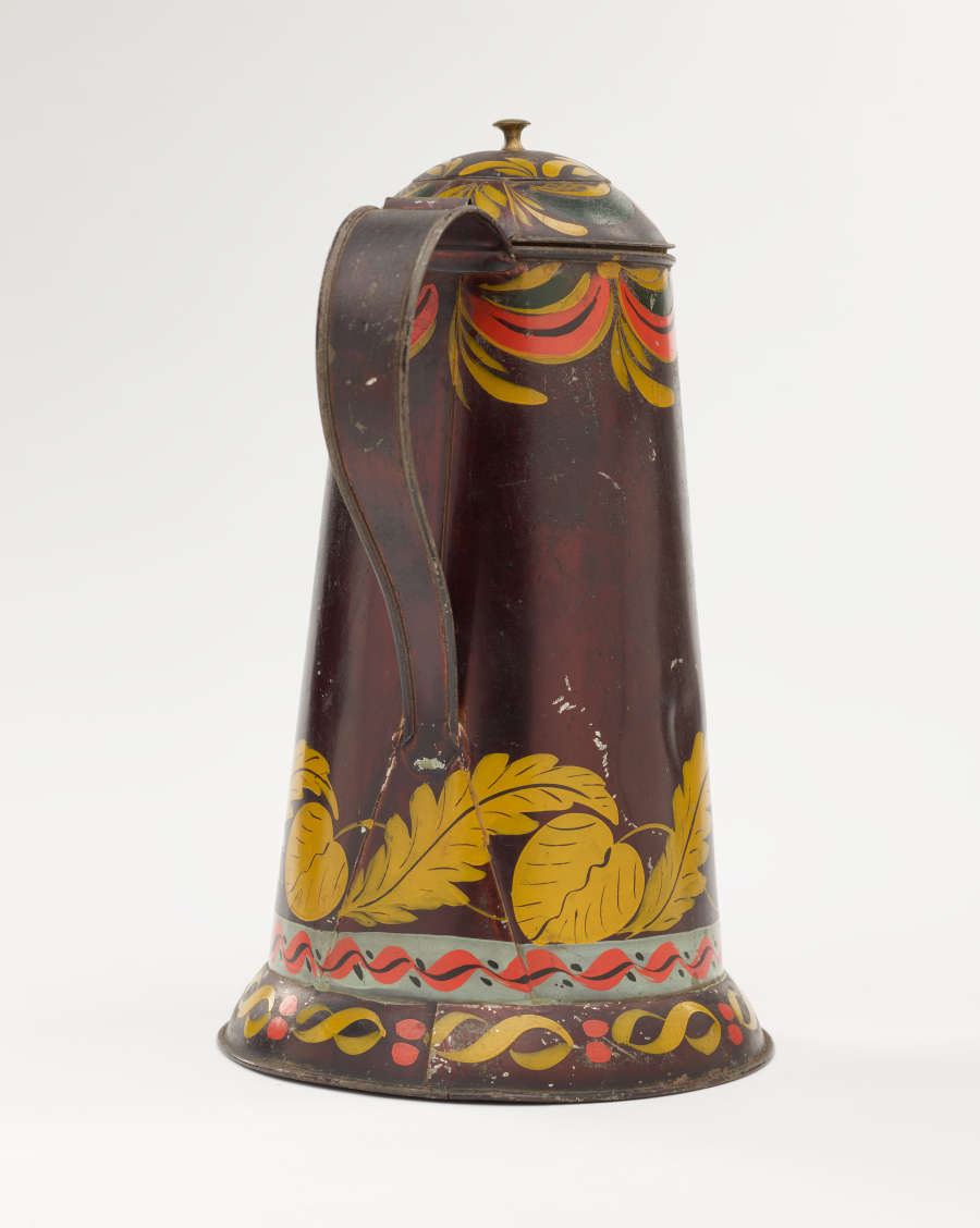 A shiny, brown colored coffee pot with yellow, white, and orange and abstract floral decoration. The spout has a right angle and then a curve.
