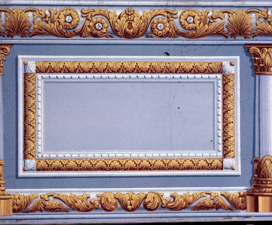 Gilded decorative border with swirling acanthus leaves framing a light blue-gray rectangular panel. The panel is flanked by Corinthian columns, also adorned with acanthus leaves, on both sides.