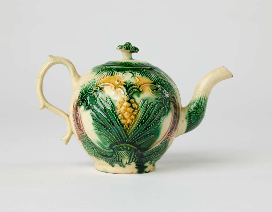 A bulbous teapot with white, green, and yellow floral decorations in the form of a leafy pineapple.