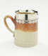 A brown and tan mug with a silver, scalloped rim.