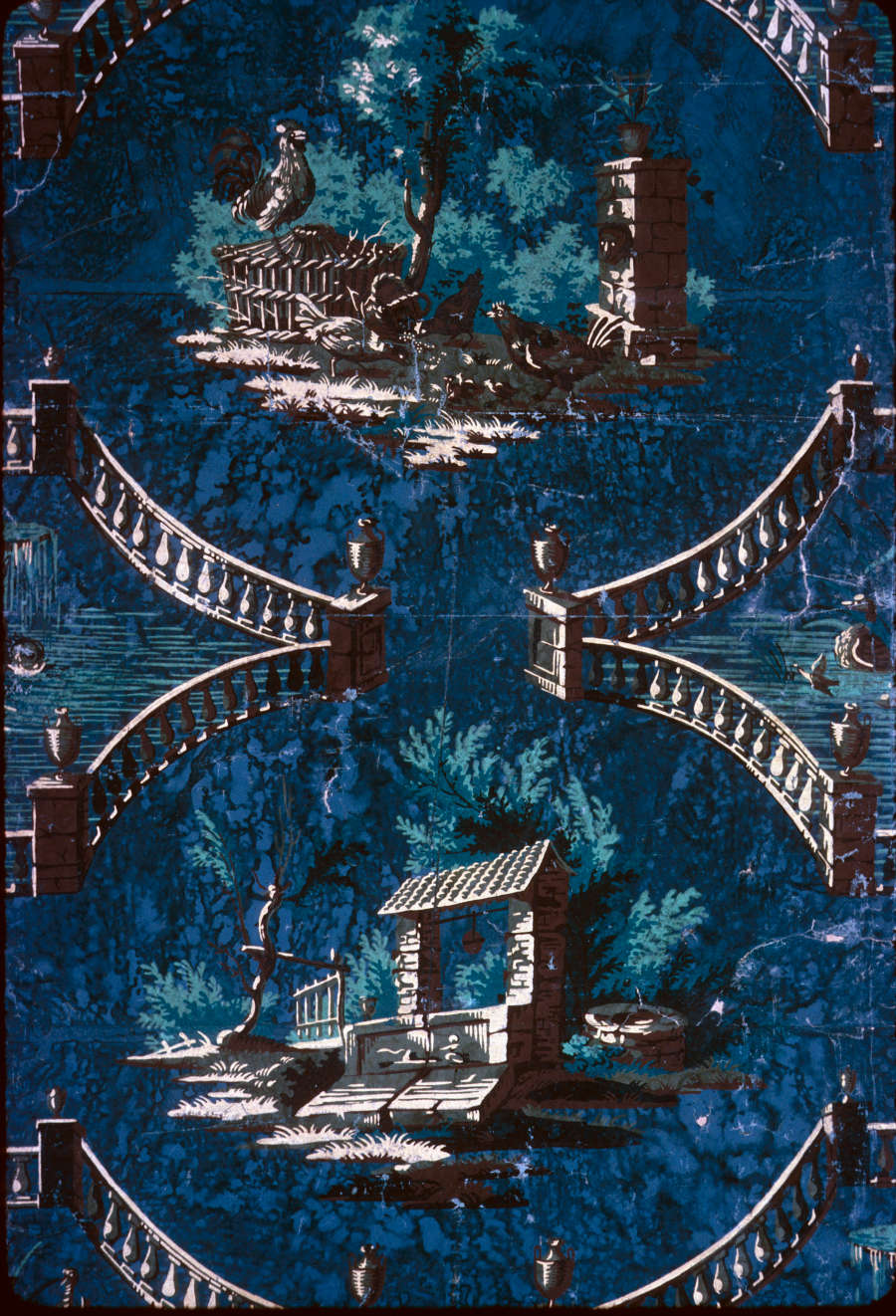 Weathered, dark blue wallpaper with repeating, pillared railing that circularly surrounds roosters standing on top and around a circular basket, and a yellow stone “housed” well below it.