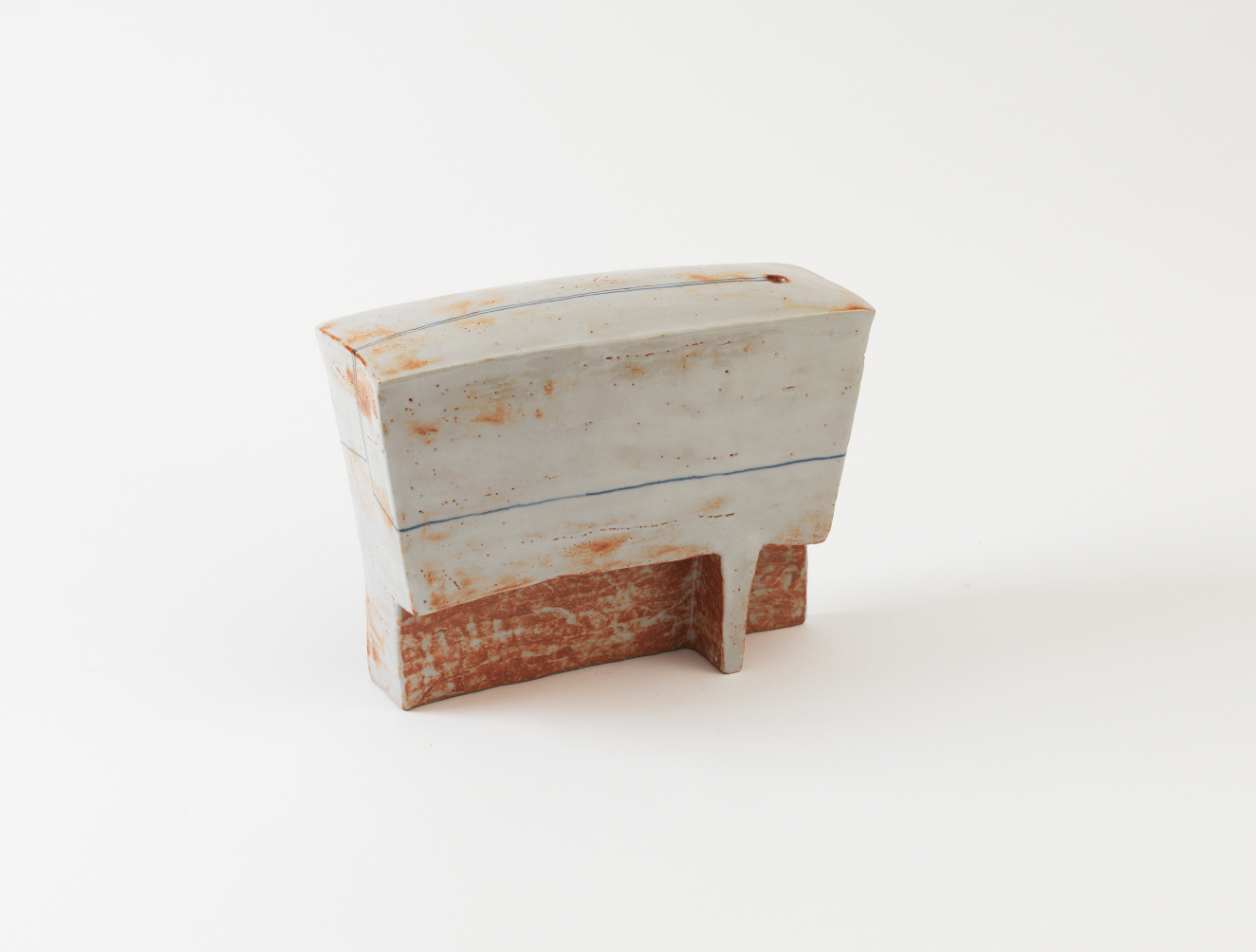 Rectangular ceramic sculpture with a pale, whitewashed surface flecked with rust colored specks, divided by a thin horizontal line above a rough, weathered red-brown base. 