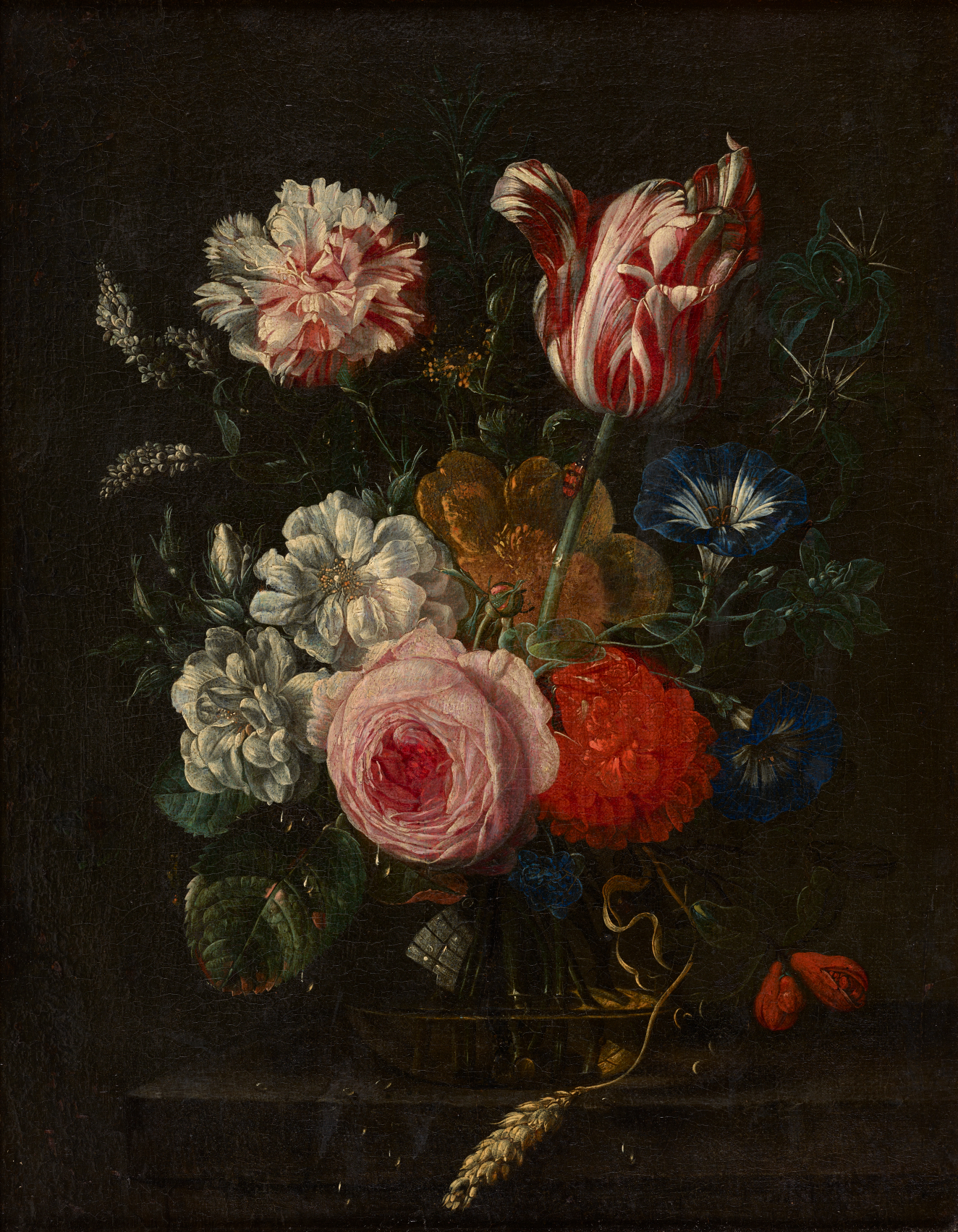 A lush bouquet of blooming, vibrant flowers, arranged in a glass vase in a dramatically lit room. 