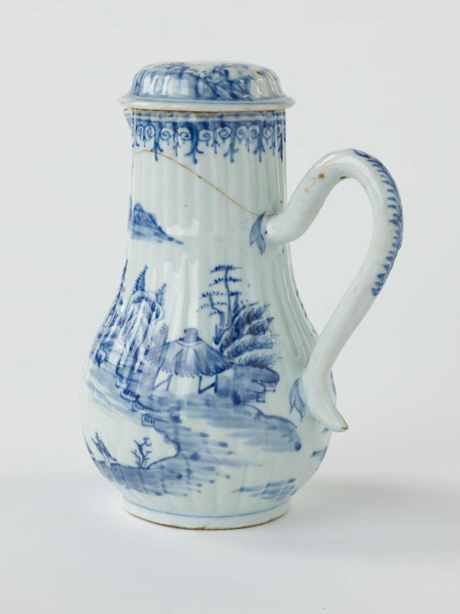 A white chocolate pot with blue decorations depicting floral and architectural elements.