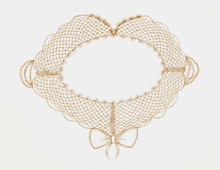 A light brown neckpiece made of bee wings arranged in a lace pattern. Four connected pieces form delicate scalloped edges, and an outline of a bow hangs from the bottom.