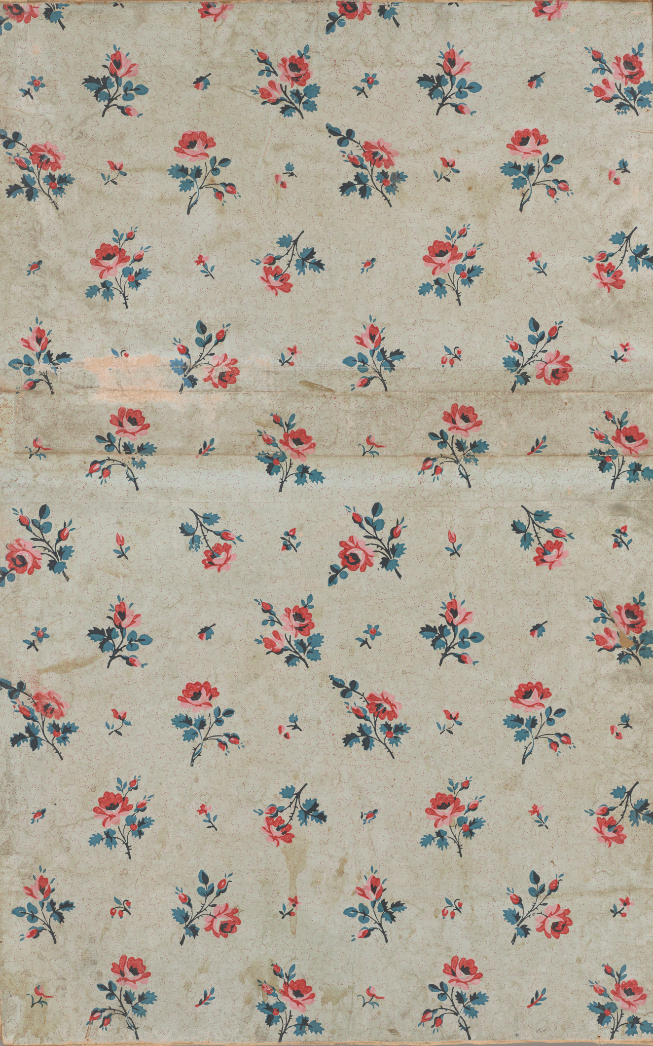 Vintage and worn beige wallpaper with a scattered floral print in pink and blue hues. The flowers are oriented randomly but evenly dispersed throughout.