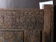 A close up of a wooden panel with intricate geometric and floral carvings, featuring a mix of square and star patterns. 