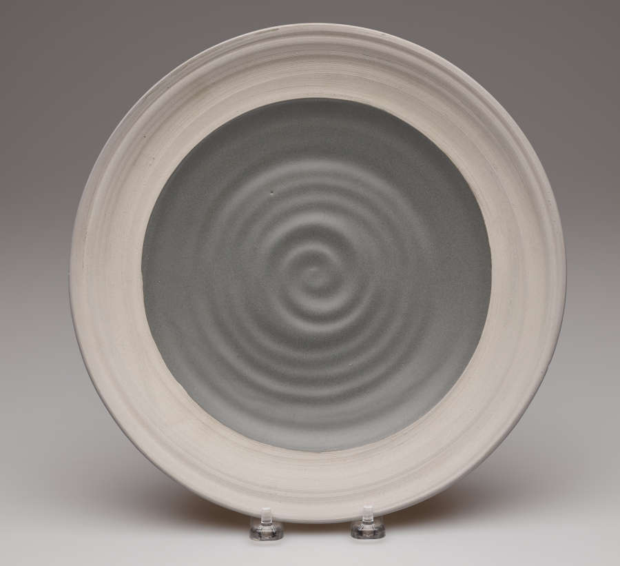 A circular plate with a spiraling dark grey center and a wide light gray rim.