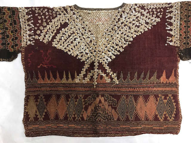 Torso of a deep red garment on a white background. The top is filled by reflective sequins while the bottom features geometric diamond and triangle motifs in orange and gray.