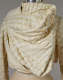 Close up of a cream colored, draped garment with a raised, netting pattern and soft folds draping across the chest. 