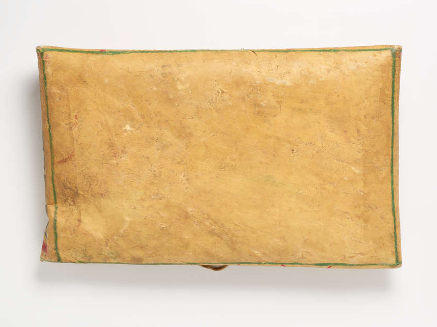Back of the tan cloth folded over into its center with a green border running along its folded edges.