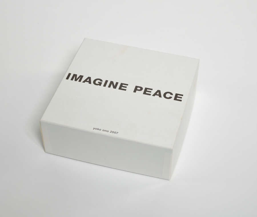 White square box with bold black text in the center which reads “Imagine Peace.” Smaller unbolded black text reads “yoko ono 2007” in the lower center region of the box.  