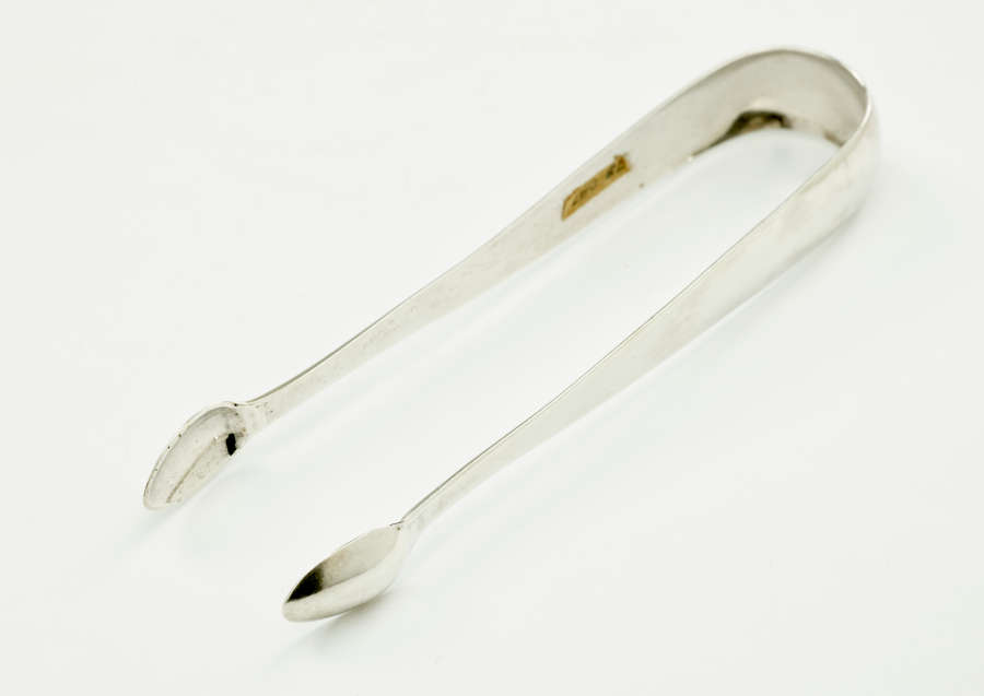 Silver sugar tongs with small ends and a thicker handle portion.
