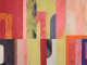Detail of the artwork’s center-left, showing light green, red, pink, black, blue and orange rectangles with fragments of orange, pink, and purple letters. The dye is wash-like and not uniform. 