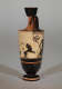 A tall, black and orange vase. Visible is a black illustration of a leaping 4-legged animal and surrounded by decorative patterns. 