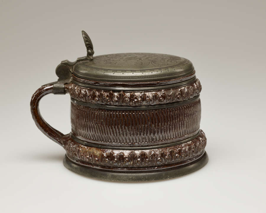 A brown and tan mug with a silver, scalloped rim.