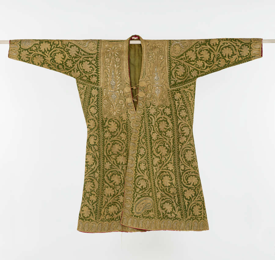 Front of a green coat with columns of gold floral embroidery.  Along the neckline are dense blocks of gold and silver embroidery with a similar strip along the sleeves’ edges.