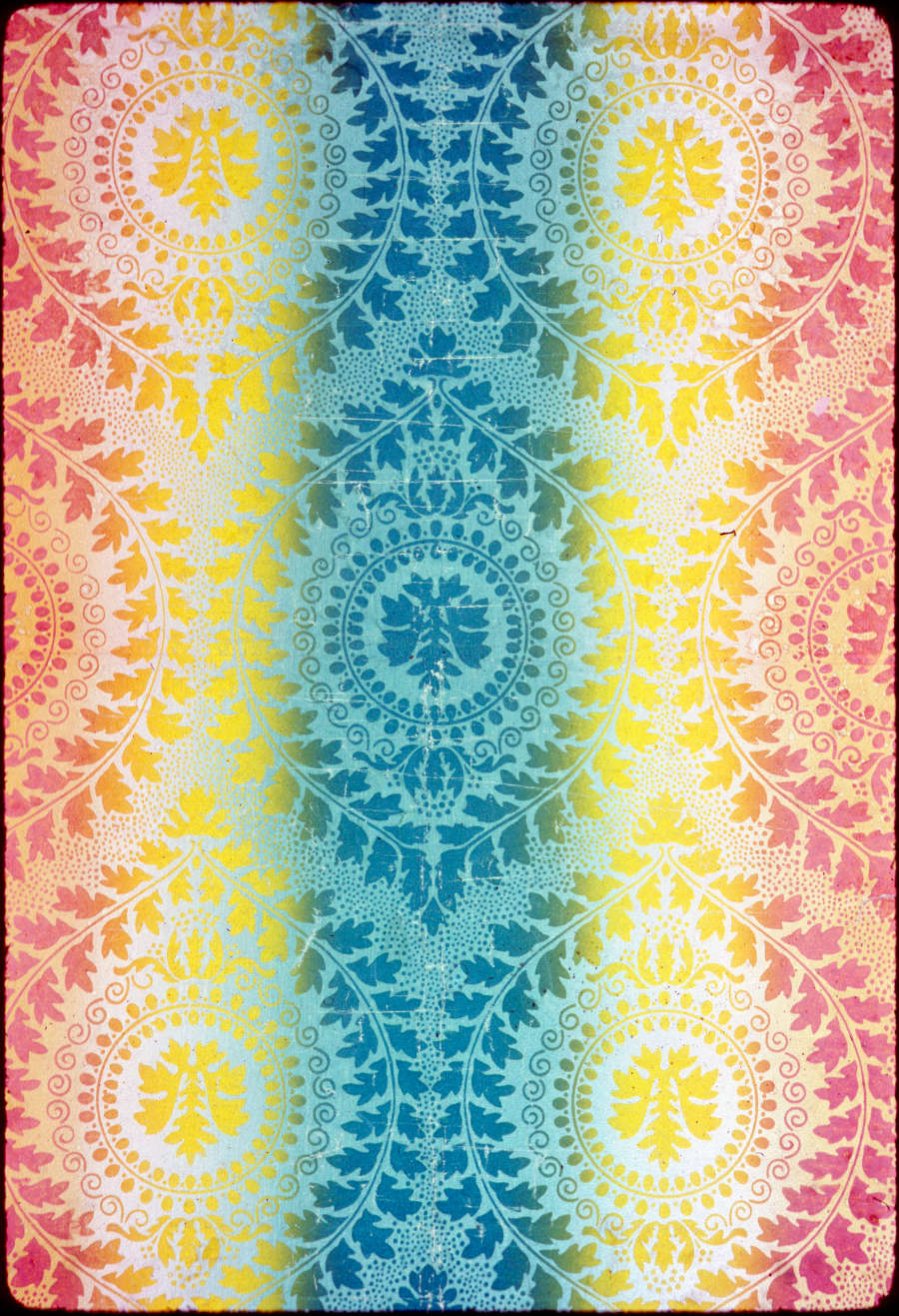 Wallpaper featuring detailed mandalas made of leaf and foliage designs that transition from a muted orange, to sunny yellow, to a cool teal at the center.