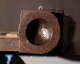 Close up of a circular end of a wooden beam with a deep, smooth, concave indentation, with evidence of age and wear. 