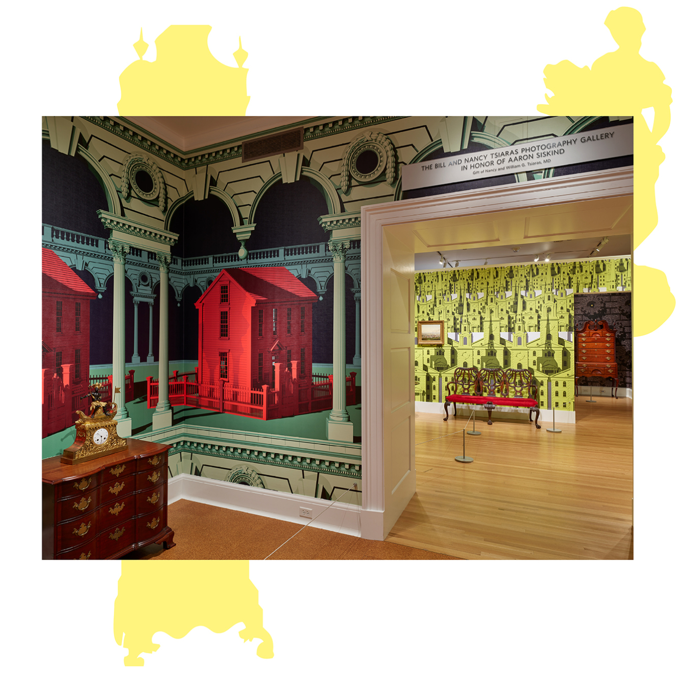 Colorful wallpaper embellishes the walls of two adjoining rooms containing antique furniture. The foreground pattern includes large vibrant red houses and green architectural details. A chartreuse pattern is adjacent.