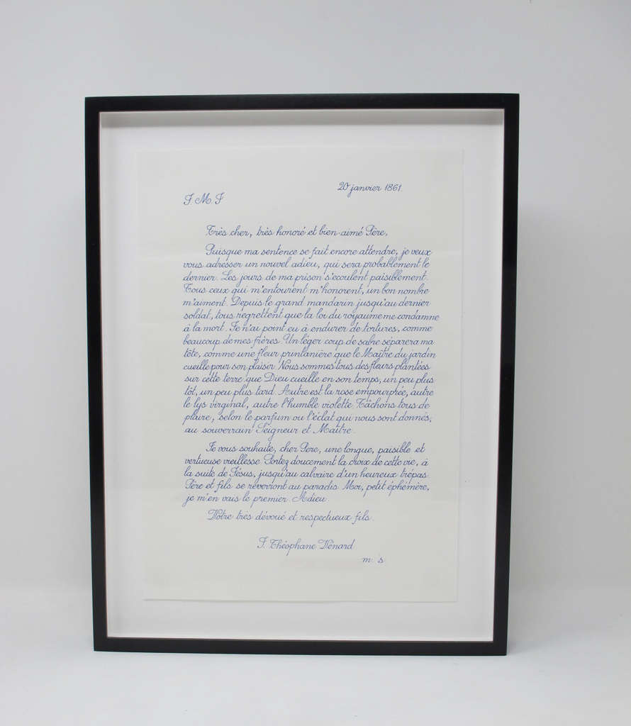 A black frame containing a blue handwritten letter on white paper against a white background. The letter is divided into four centered paragraphs with a date, greeting, farewell, and signature. 