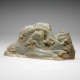 A pale green, smooth jade carving resembling mountain peaks dotted with clustered tree and a small waterfall in the center. 