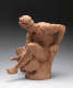 Terracotta statue depicting a realistically carved muscular bearded man facing left, his bent arm supporting him from behind while his leg wraps over the vessel he’s leaning over to hold.