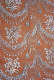 Intricate and elegant patterns of draping florals and tassel motifs done in white appear embossed on a warm dark orange backdrop